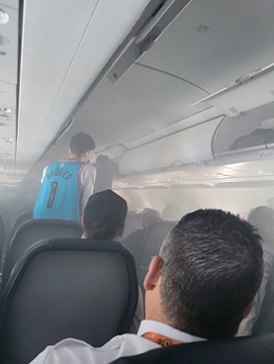 Smoke spirals through an aircraft passenger cabin during a lithium battery incident