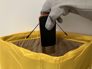 A portable battery charger being placed in an AvSax lithium fire mitigation bag